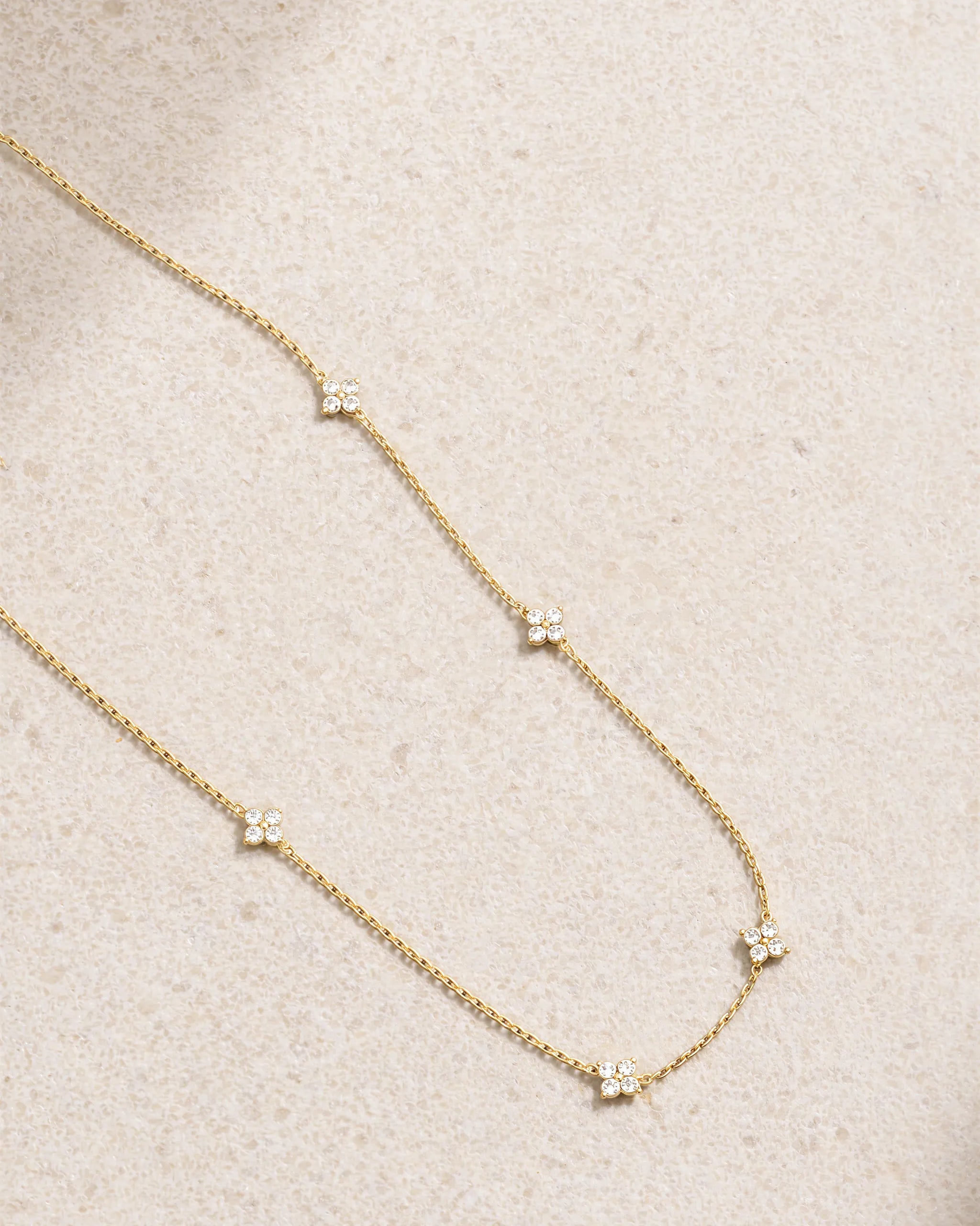 Delicate gold necklace with small diamonds on a beige fabric background