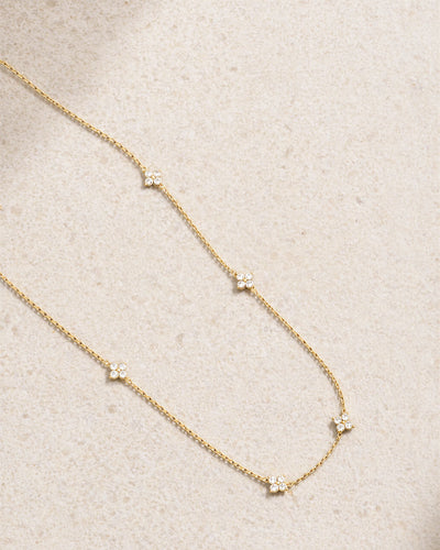 Delicate gold necklace with small diamonds on a beige fabric background
