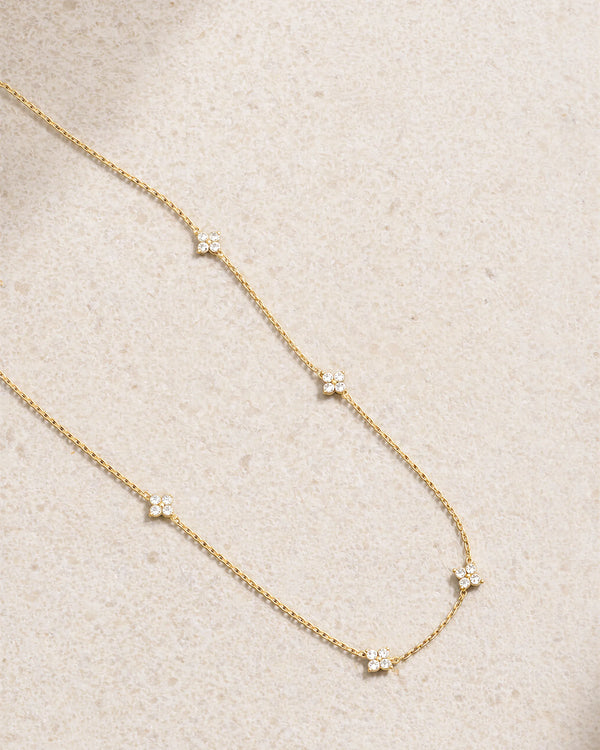 Delicate gold necklace with small diamonds on a beige fabric background