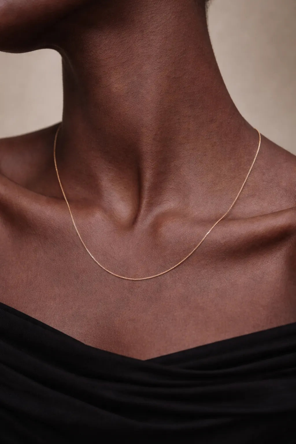 Gold necklace on a person with a neutral background