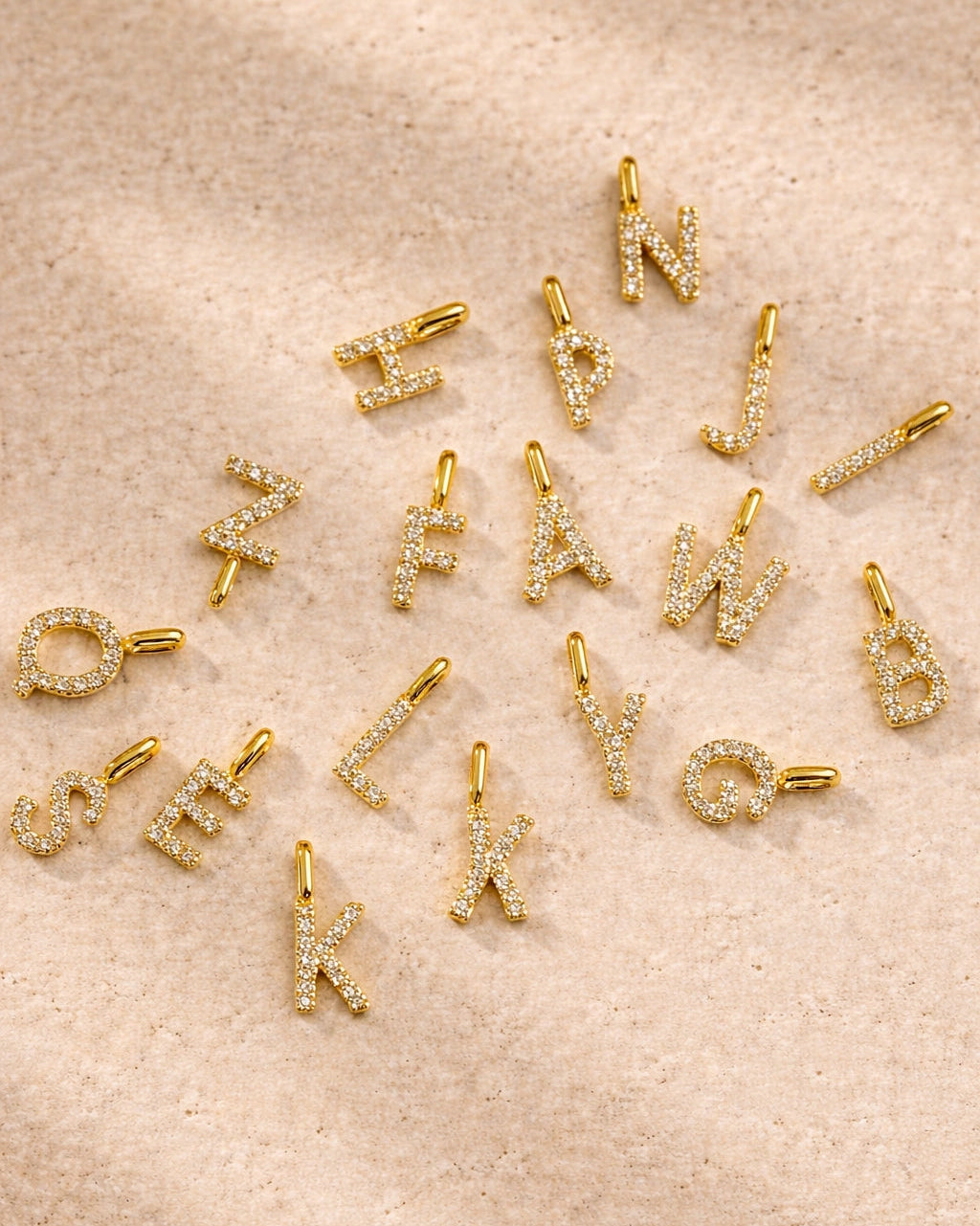 Gold letter charms on a beige surface