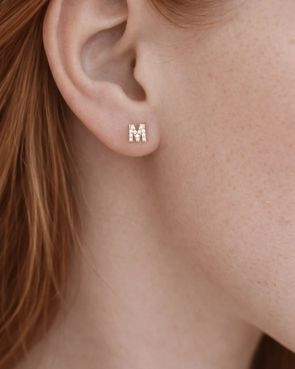 Close-up of a person wearing gold butterfly earrings.