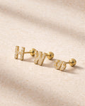 Gold earrings with 'H' and 'W' on a beige fabric background