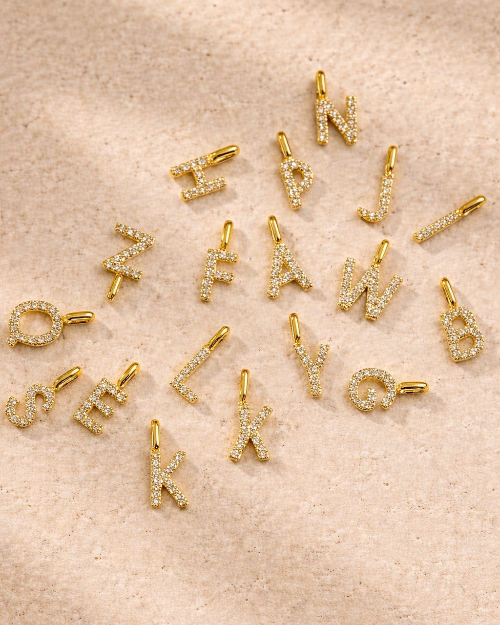 Gold letter charms on a beige surface