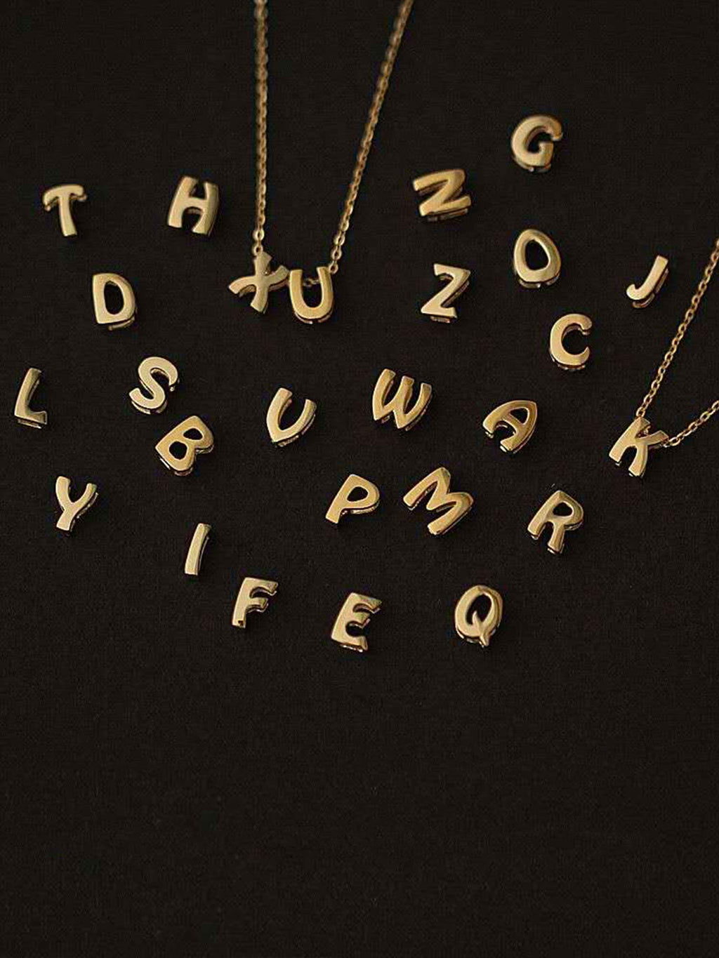 Gold letter pendants on a black background