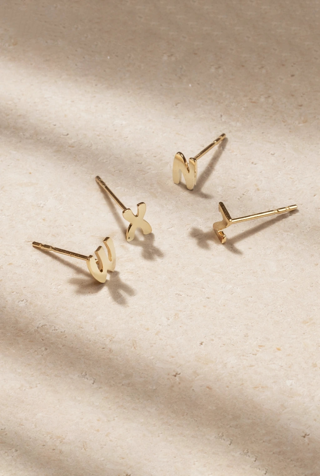 Set of gold earrings on a beige fabric background