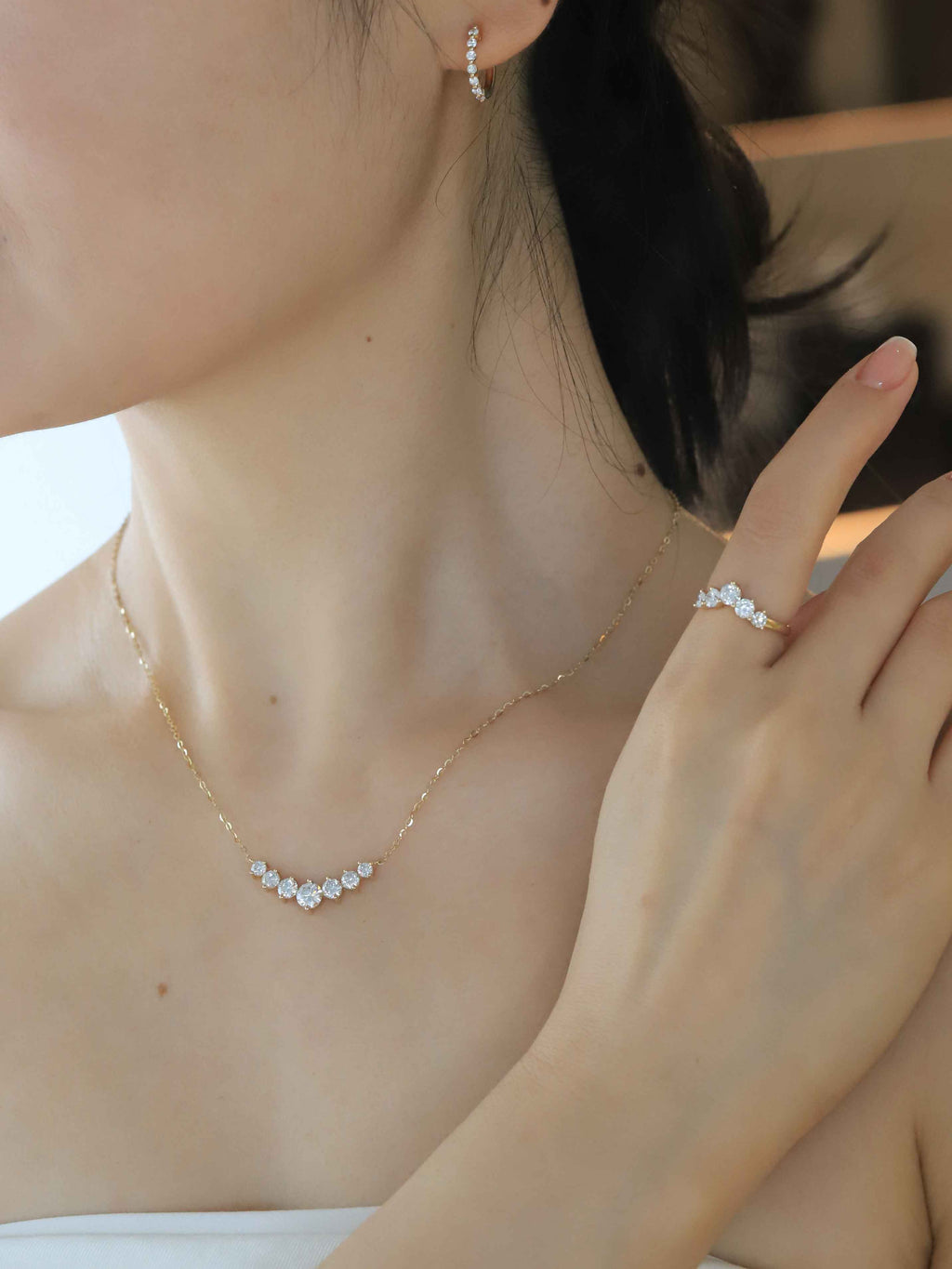 Close-up of a person wearing gold jewelry including a necklace and earrings.