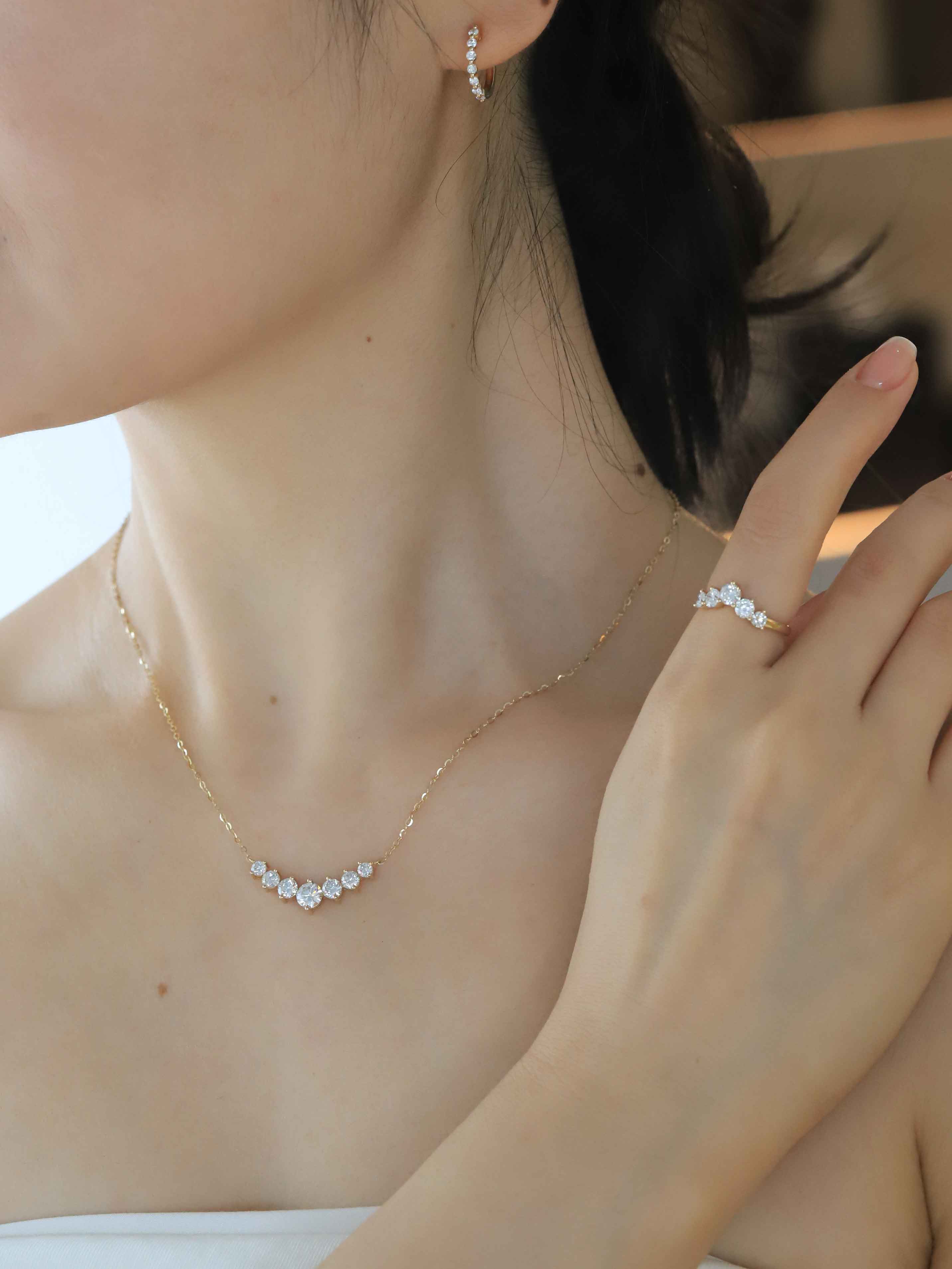 Close-up of a person wearing gold jewelry including a necklace and earrings.