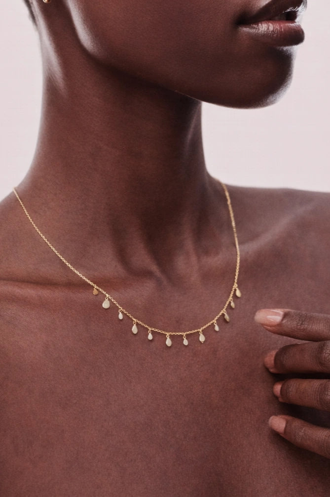 Necklace with small droplet pendants on a model against a neutral background