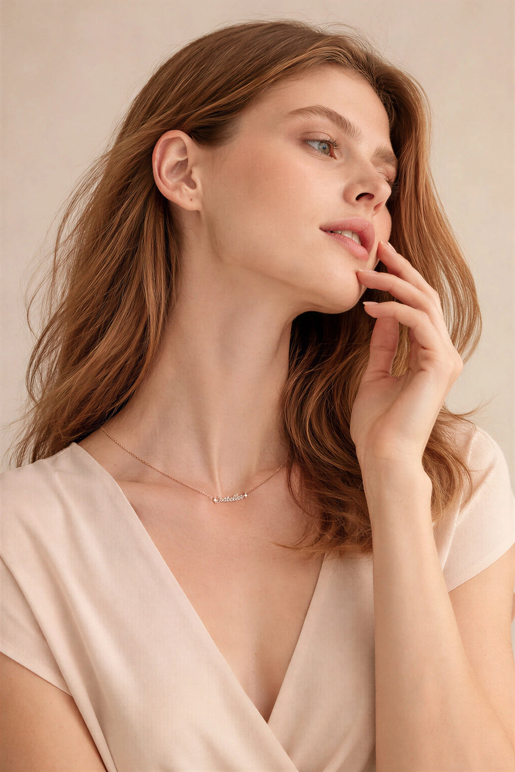 Woman wearing a delicate necklace against a neutral background