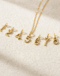 Gold necklace with number pendants on a light beige background