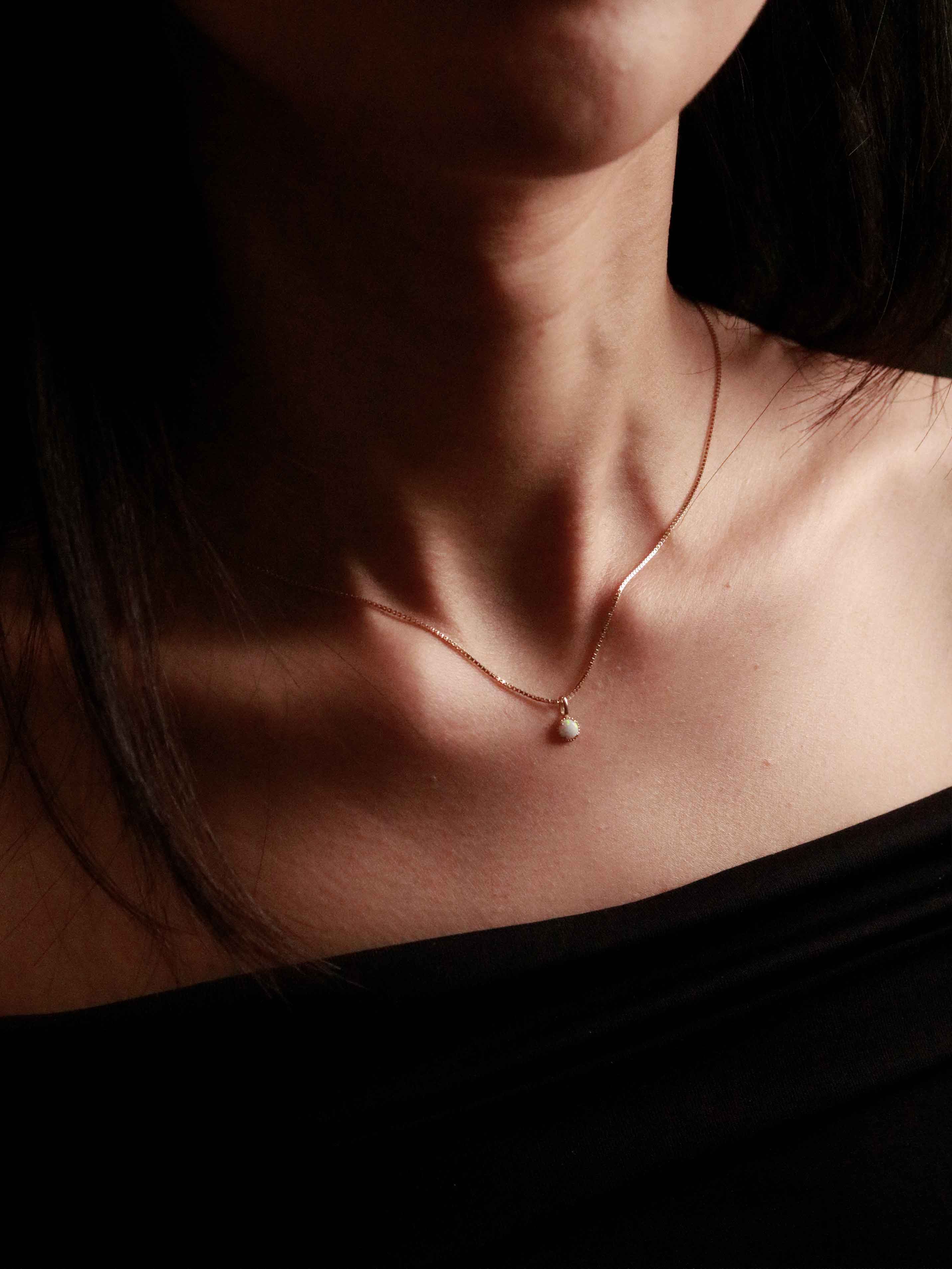 necklace with a pendant on a person wearing a black top.