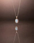 Necklace with an opal pendant on a reflective surface