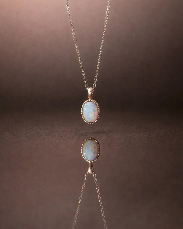 Oval opal pendant necklace in solid gold on a model against a soft pink background