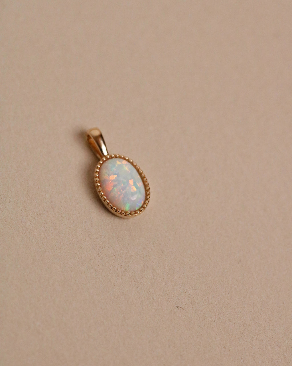 Opal pendant in a gold setting on a beige background