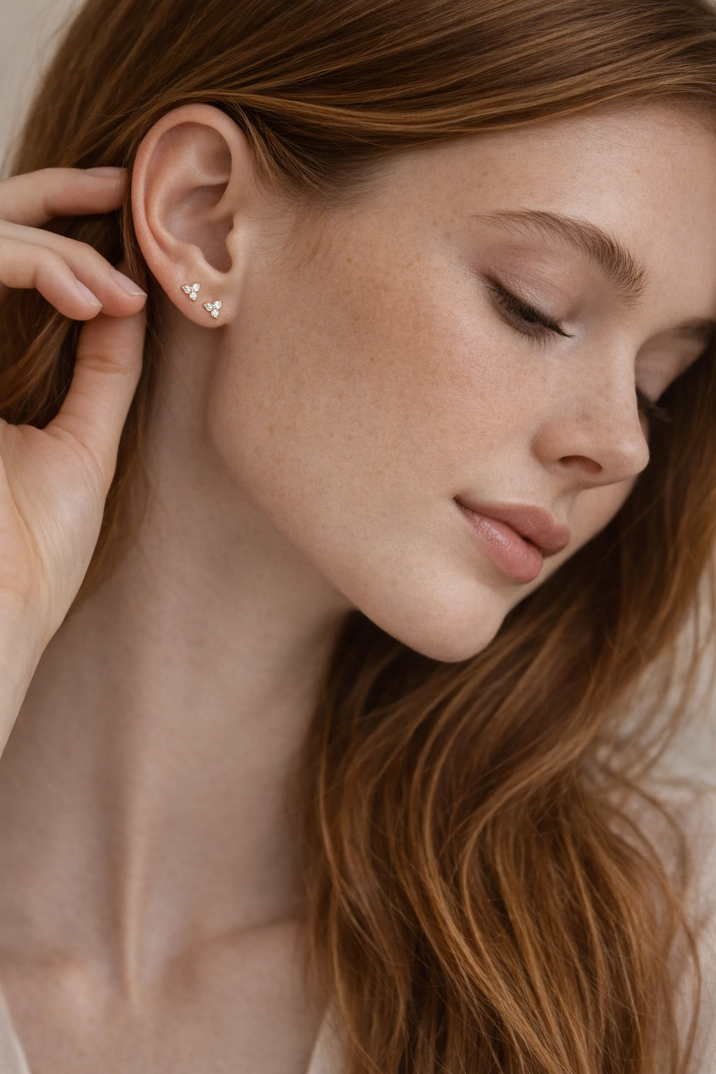 Close-up of a woman wearing a diamond earring with a neutral background