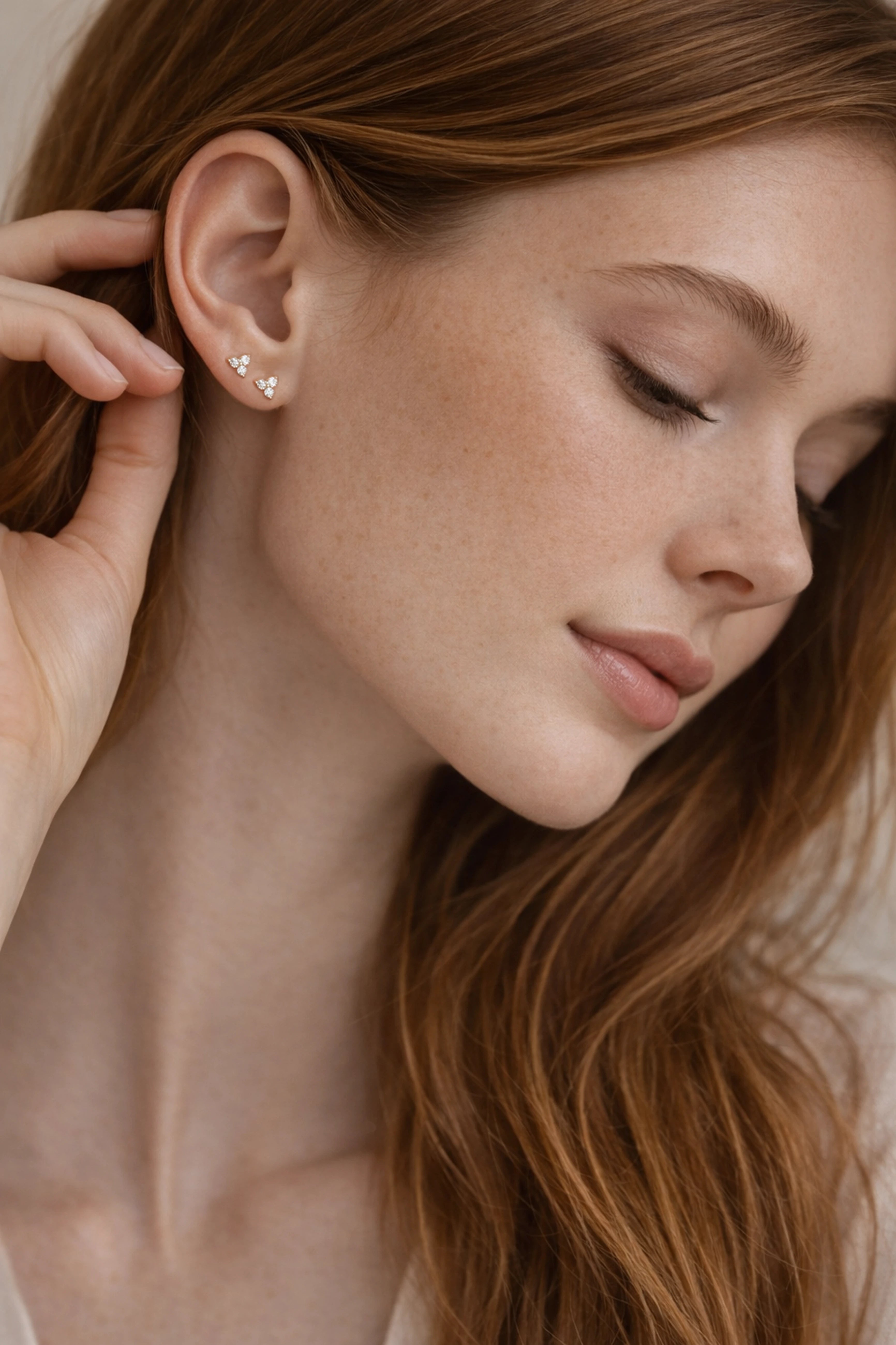 Close-up of a woman wearing a diamond earring with a neutral background